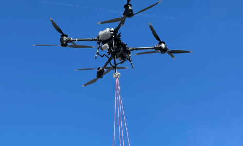 Drone flying in sky with payload attached